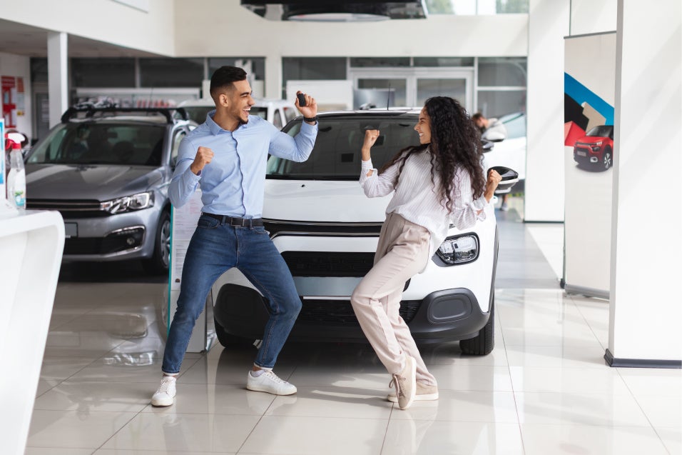 Couple dancing infront of new white SUv at Casa Buick GMC